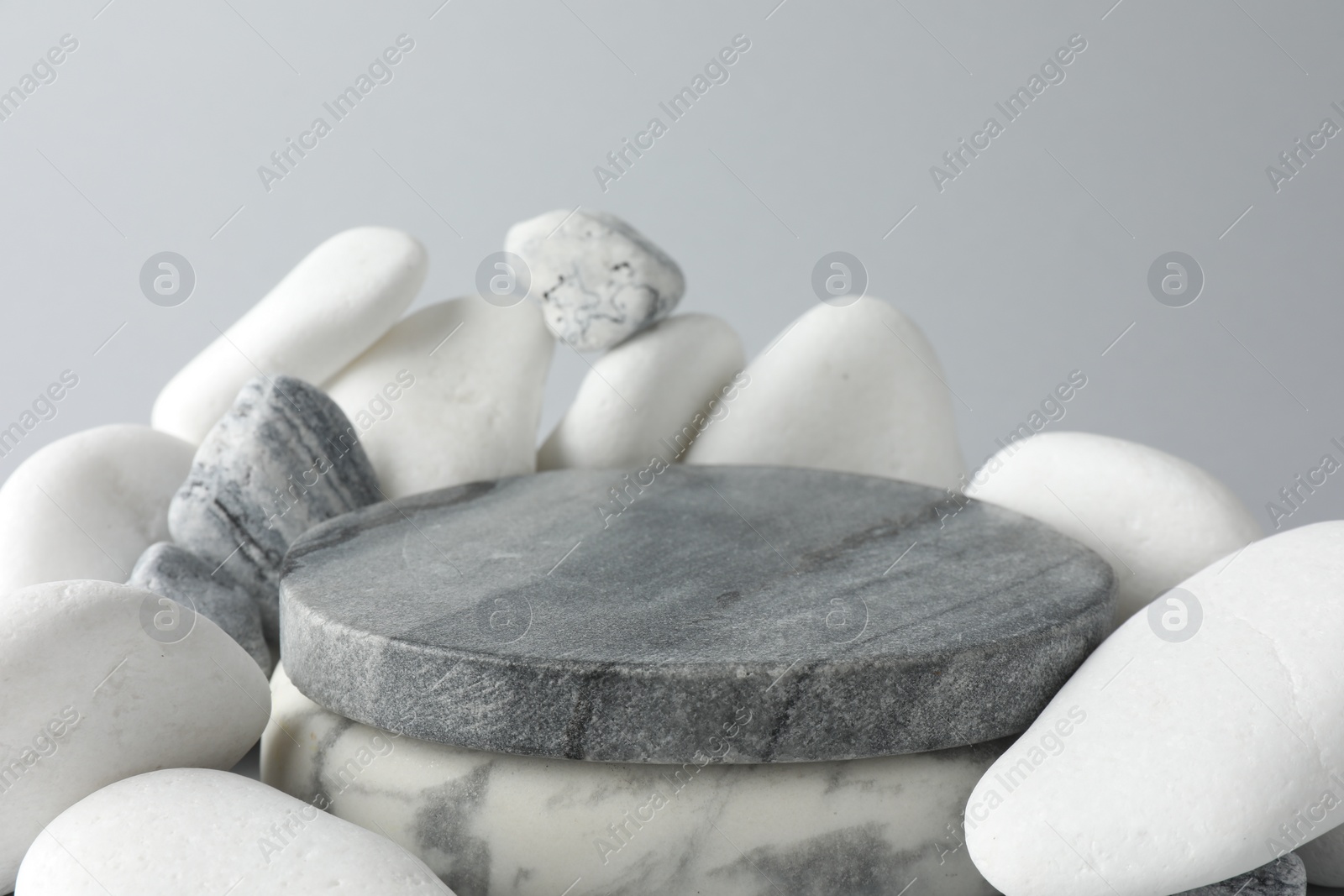 Photo of Presentation for product. Stone podium and pebbles on light grey background, closeup