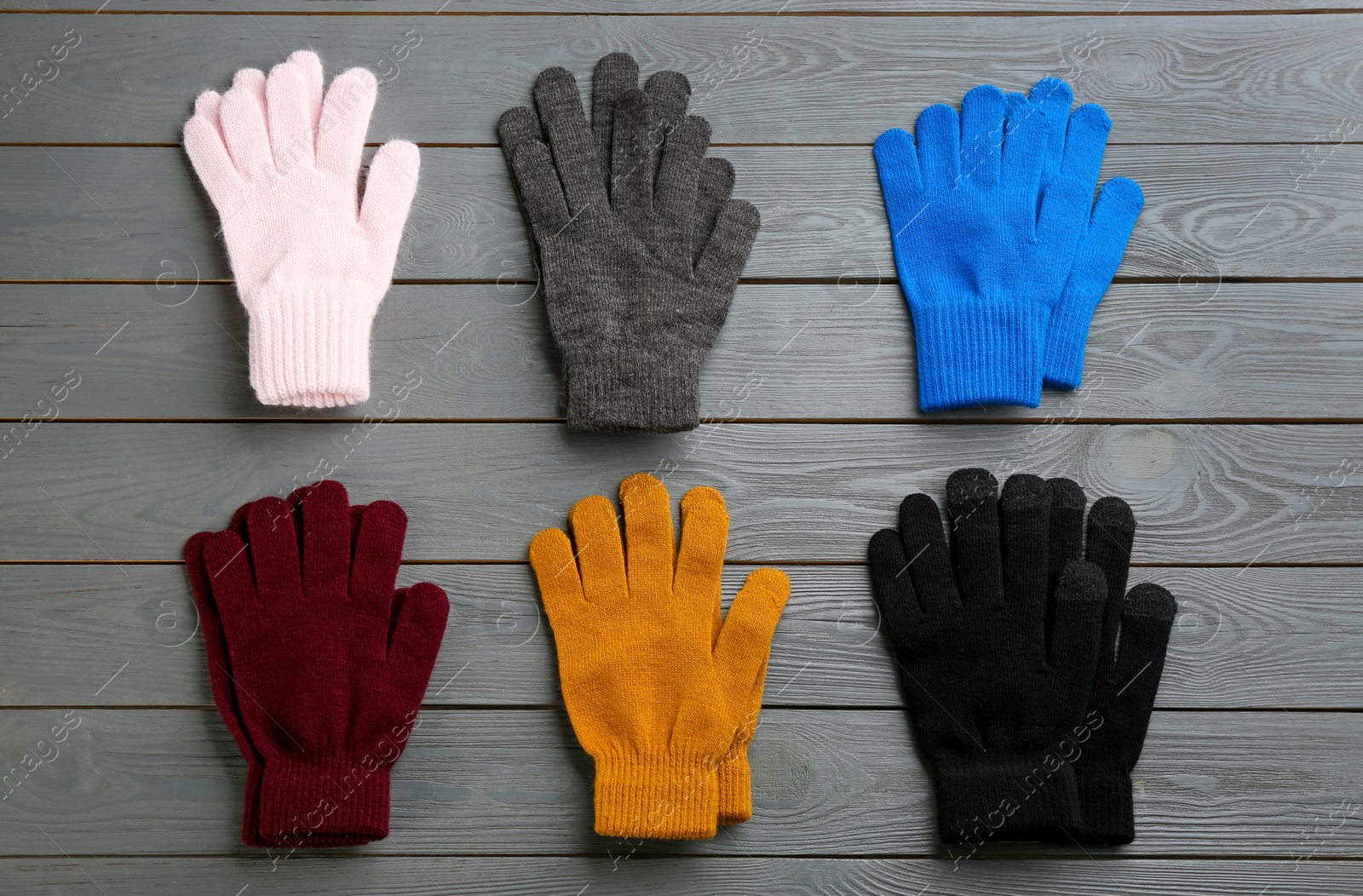 Photo of Set of stylish gloves on grey wooden background, flat lay