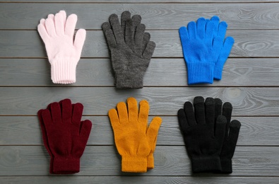 Set of stylish gloves on grey wooden background, flat lay