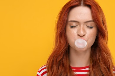 Photo of Beautiful woman with closed eyes blowing bubble gum on orange background. Space for text