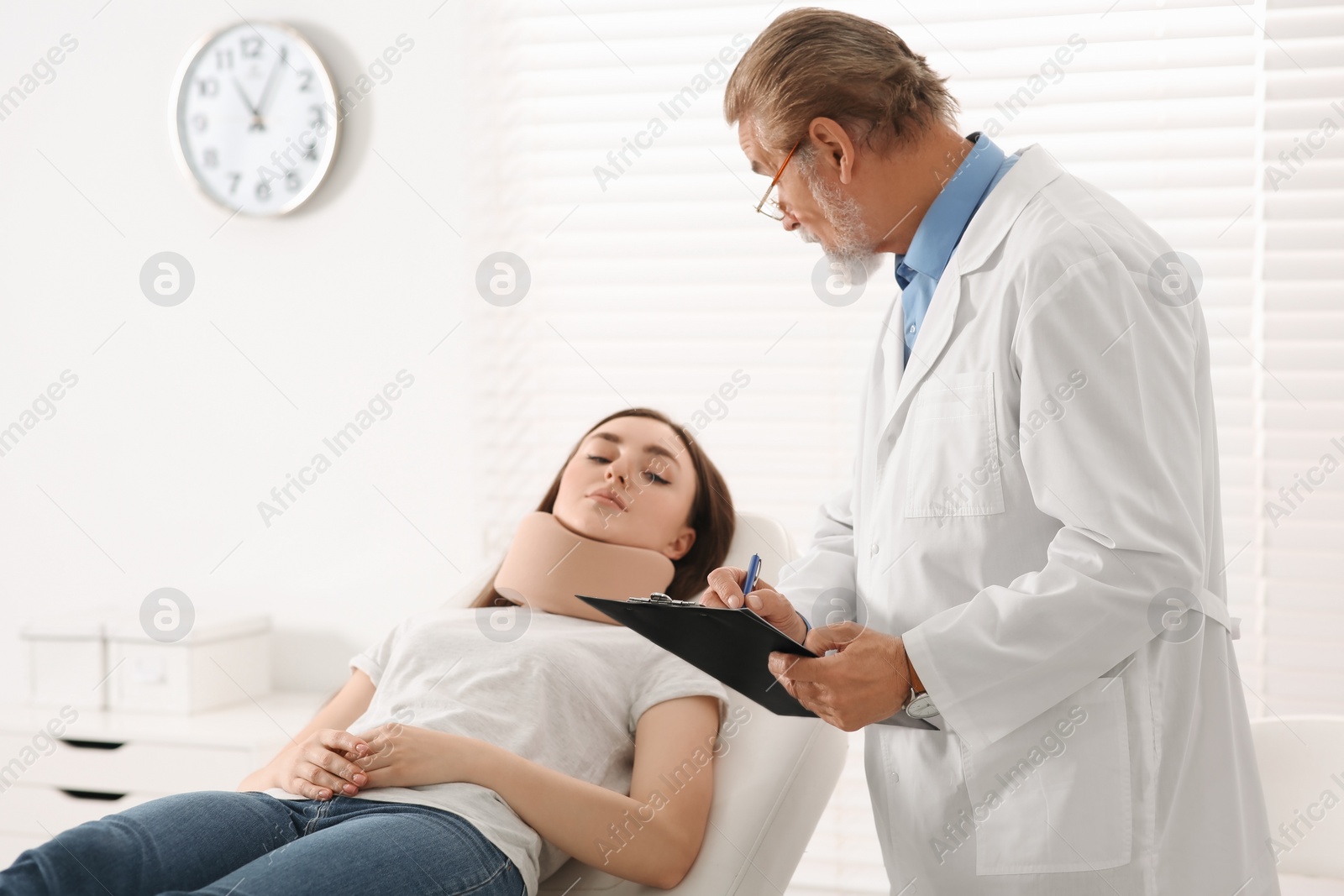 Photo of Orthopedist examining patient with injured neck in clinic