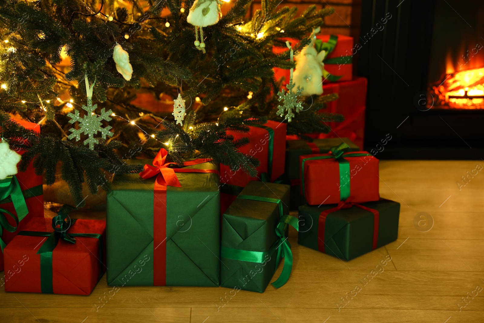 Photo of Beautifully wrapped gift boxes under Christmas tree indoors