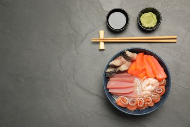 Photo of Delicious mackerel, salmon, shrimps and tuna served with funchosa, wasabi and soy sauce on grey table, flat lay with space for text. Tasty sashimi dish
