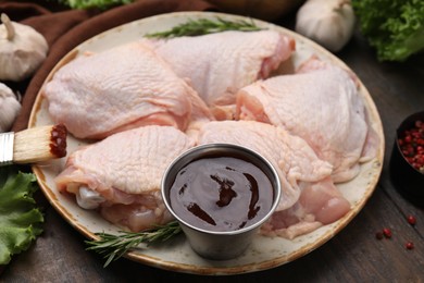 Photo of Plate with fresh marinade, raw chicken and rosemary on wooden table, closeup