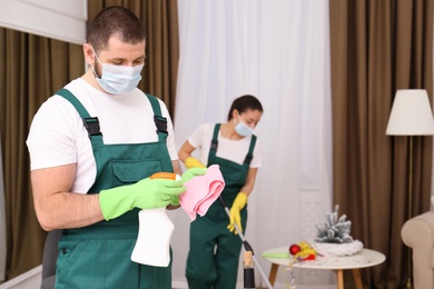 Cleaning service team working in messy room after New Year party