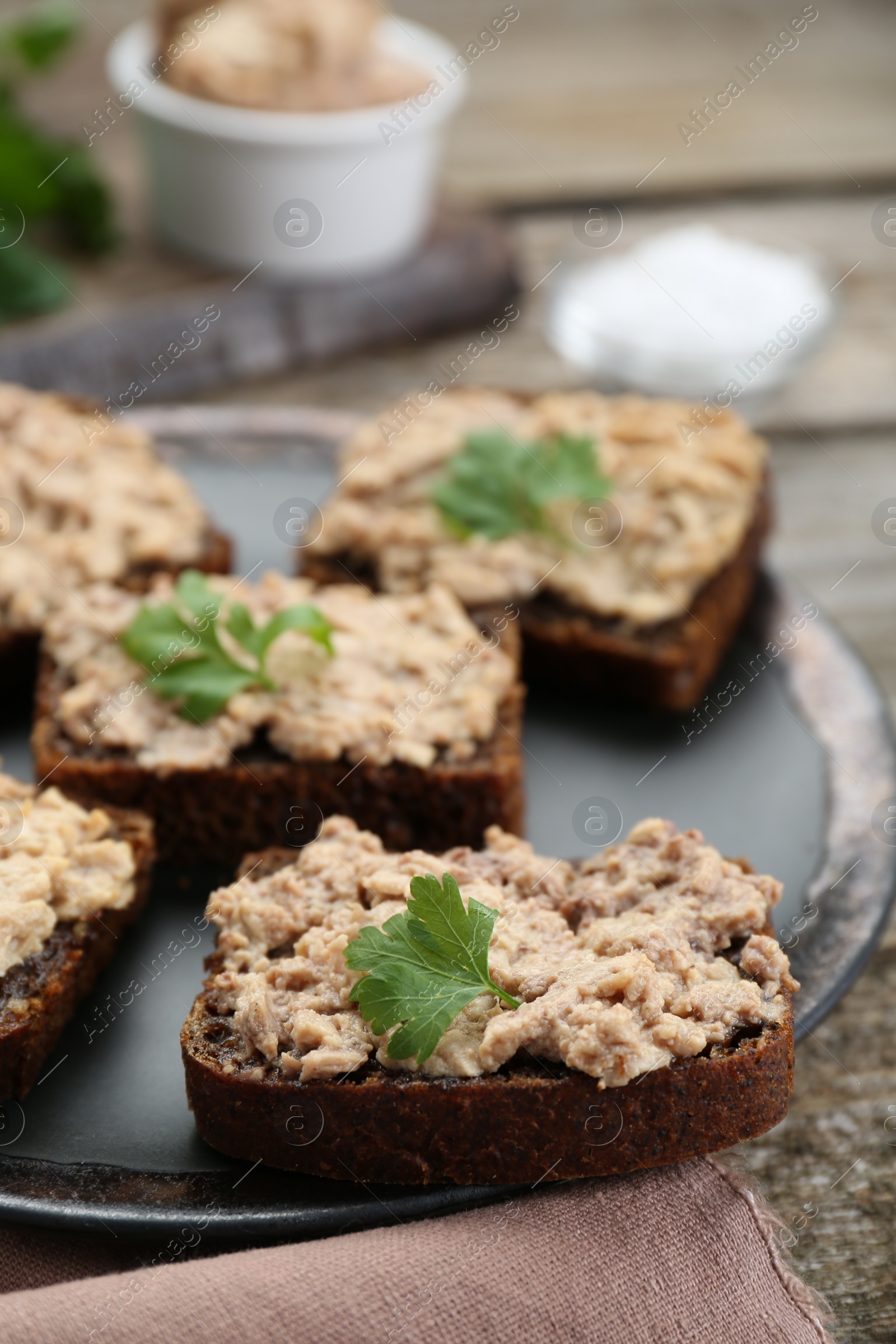 Photo of Tasty sandwiches with cod liver and parsley on wooden table