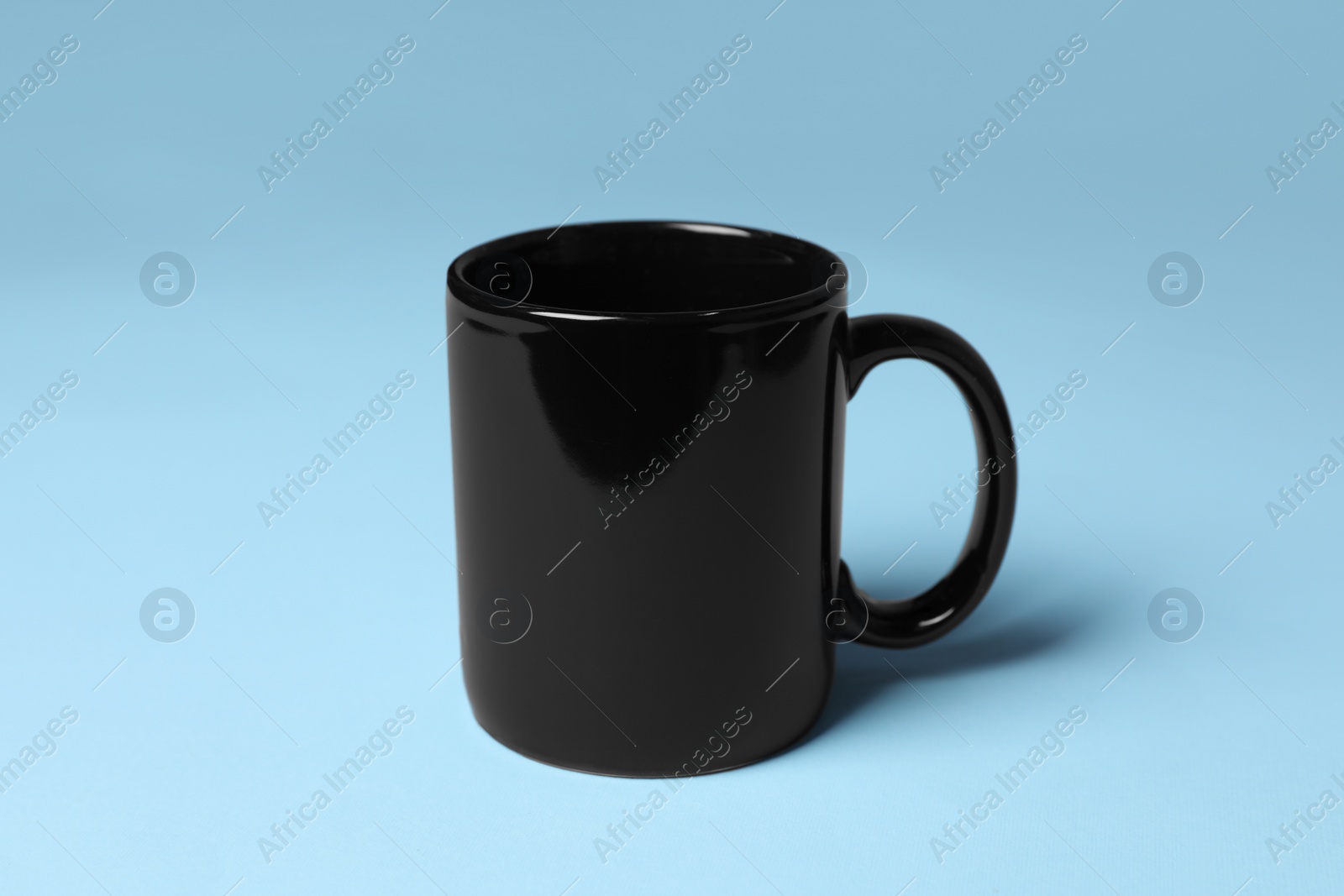 One black ceramic mug on light blue background Photo of One black ceramic mug on light blue background