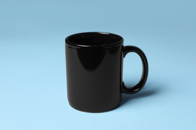 Photo of One black ceramic mug on light blue background