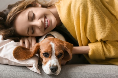 Young woman with her dog resting on sofa at home