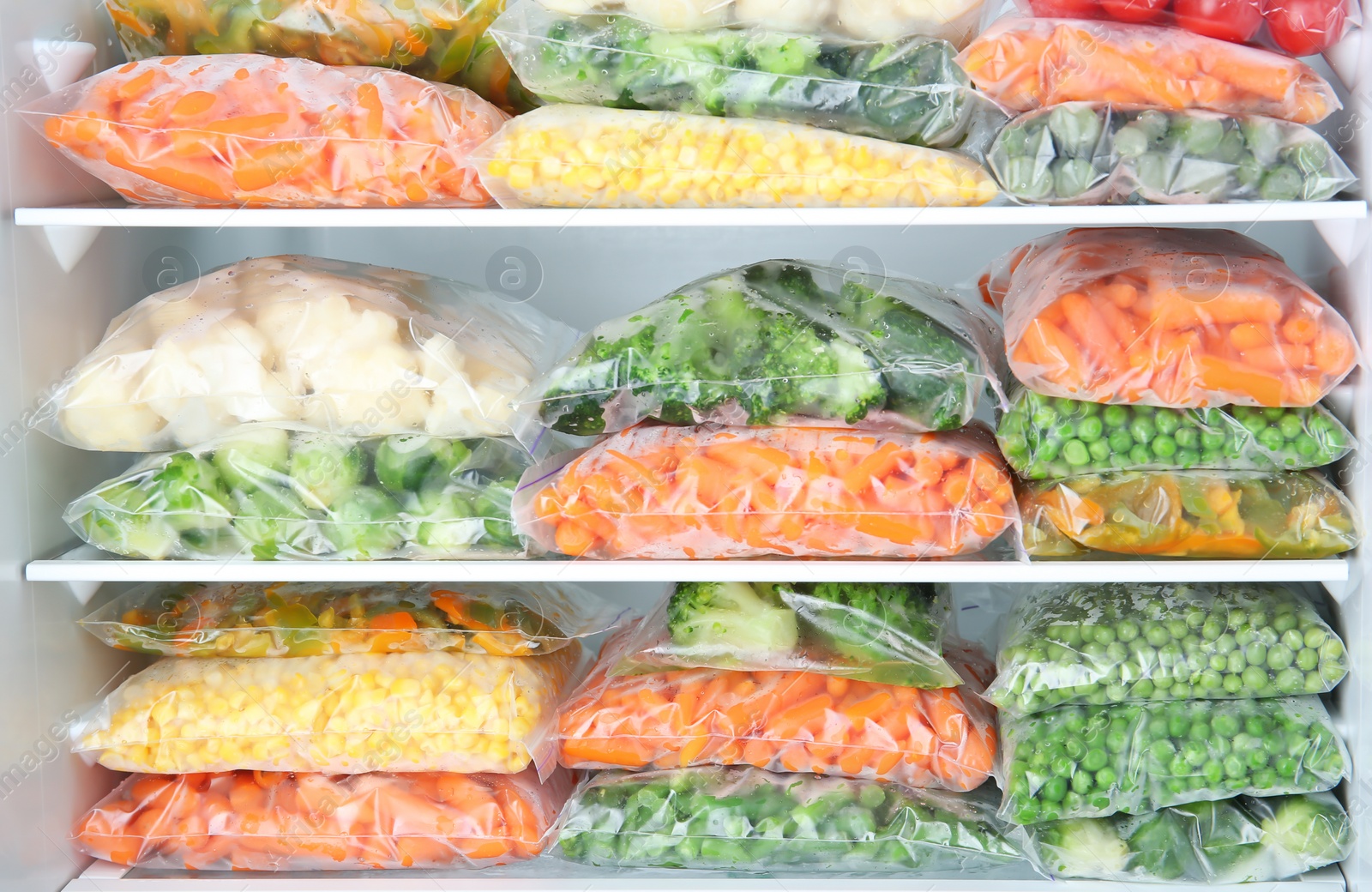 Photo of Plastic bags with deep frozen vegetables in refrigerator