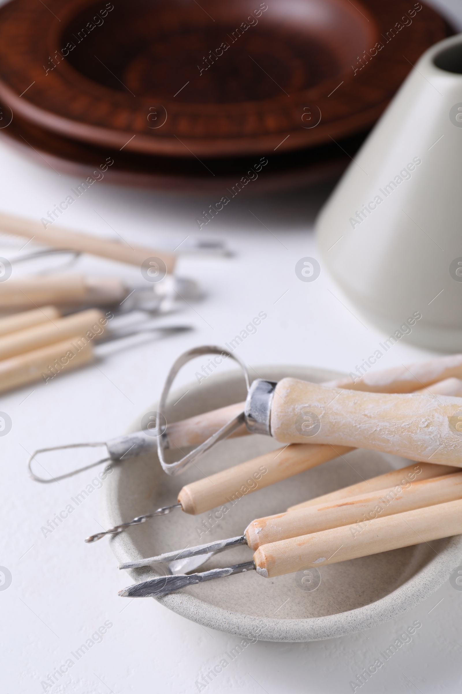 Photo of Set of different clay crafting tools on white table