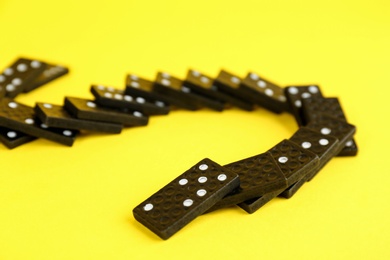 Falling black domino tiles on yellow background