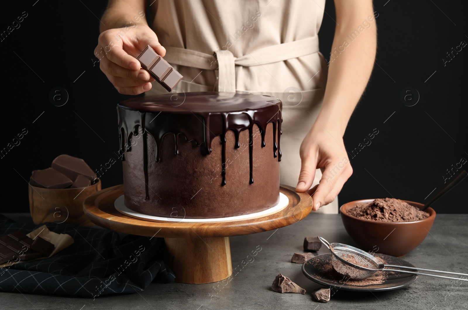 Photo of Chef making fresh delicious chocolate cake at grey table, closeup