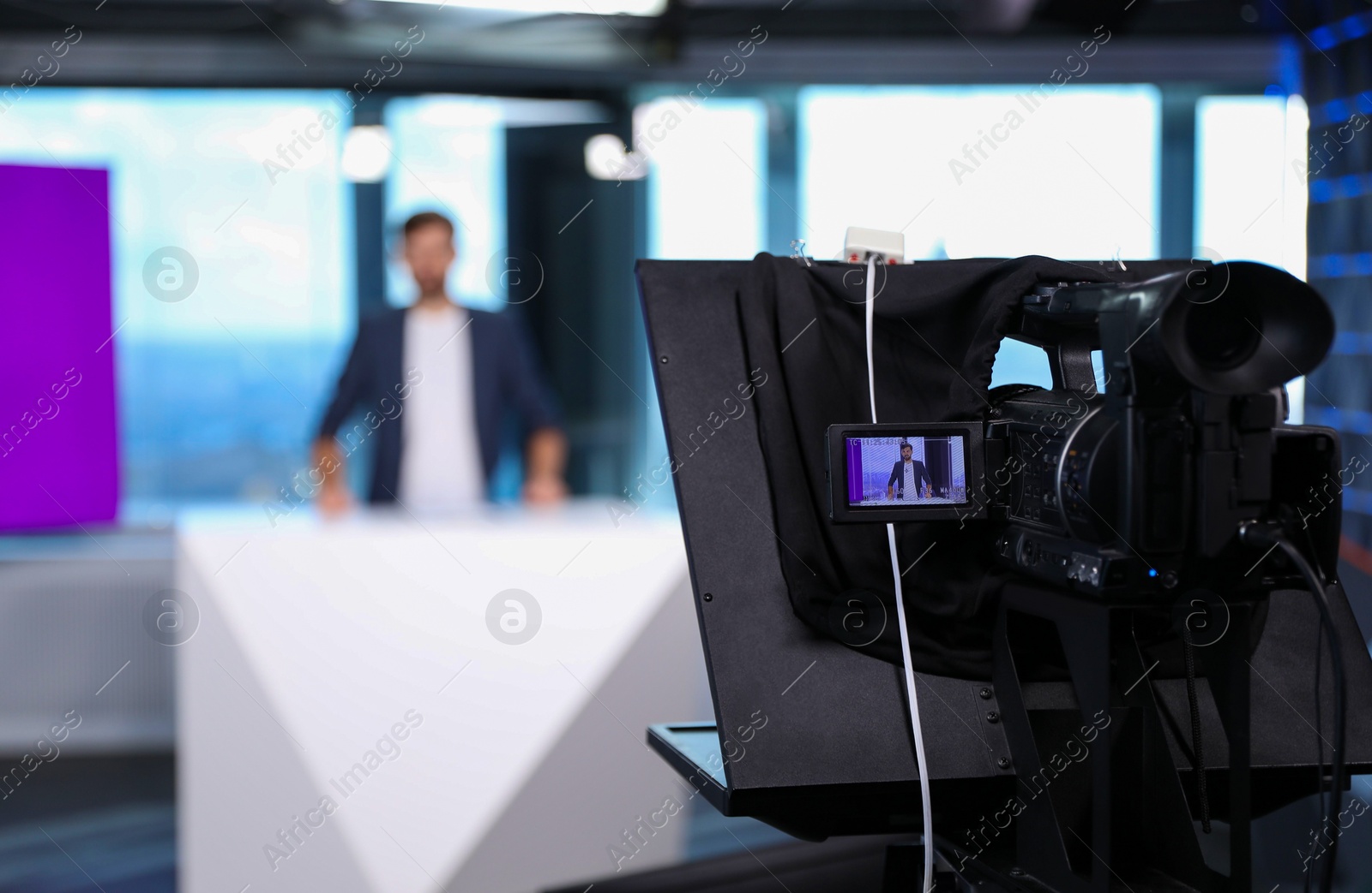 Photo of Presenter working in studio, focus on video camera