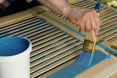 Man painting wooden surface with blue dye outdoors, closeup