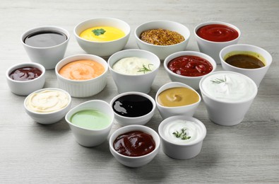 Photo of Many different sauces on white wooden table