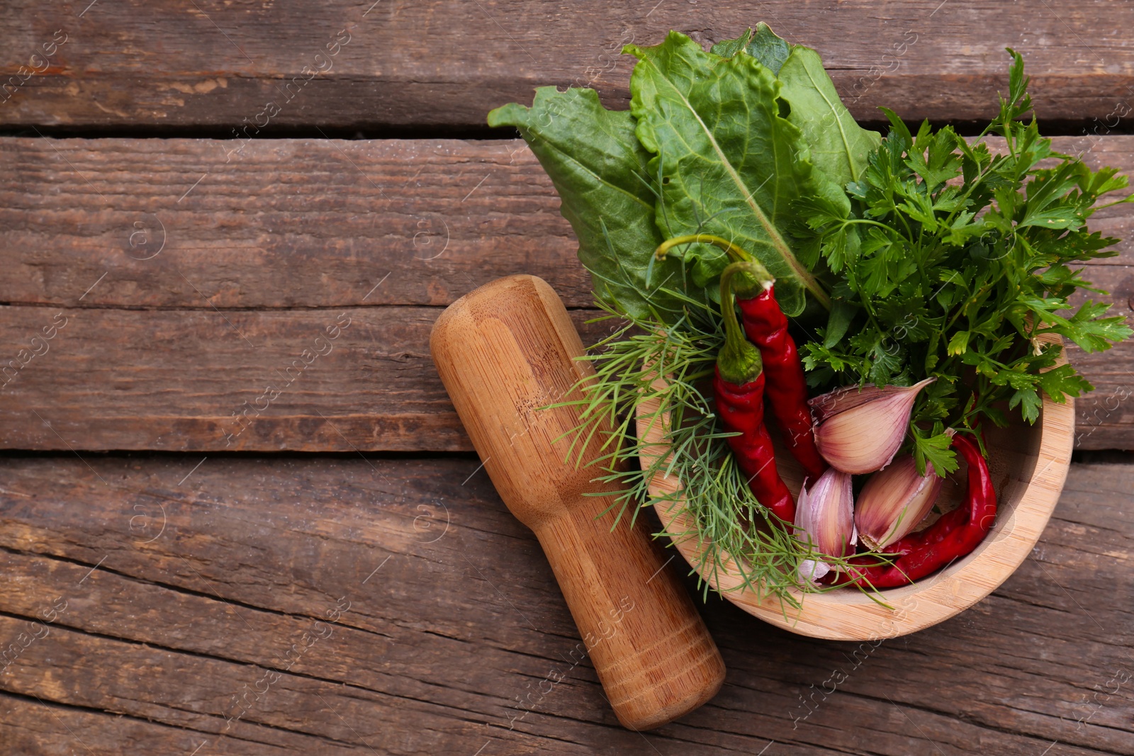 Photo of Mortar with pestle and different ingredients on wooden table, top view. Space for text