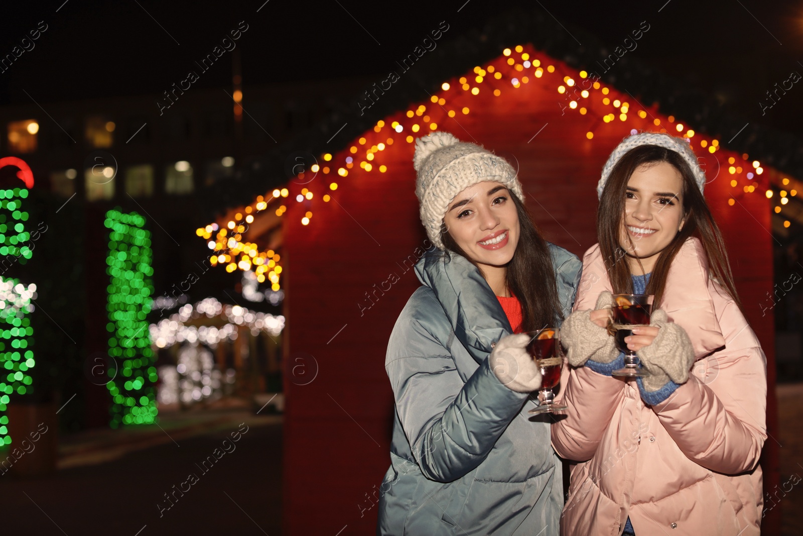 Photo of Friends with glass cups of mulled wine at winter fair. Space for text