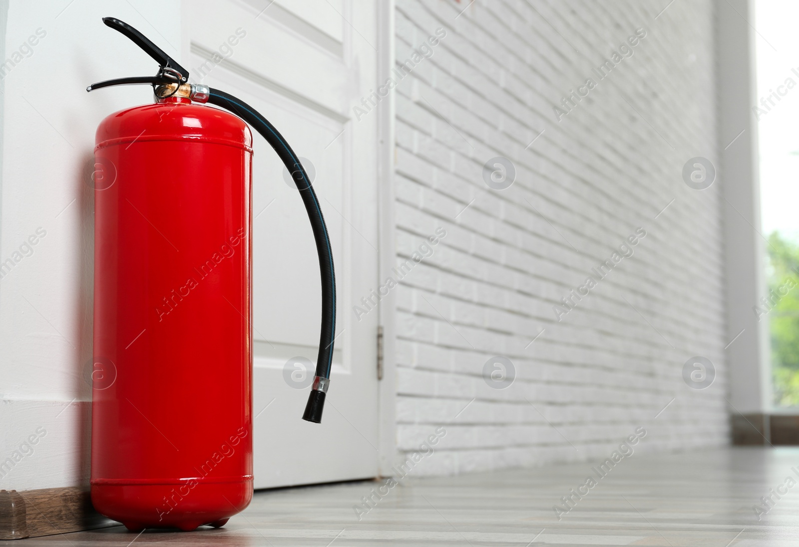 Photo of Fire extinguisher on floor near door indoors, space for text