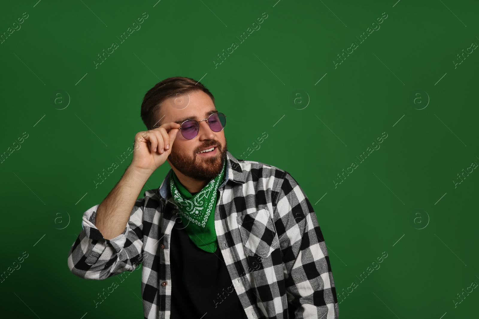 Photo of Fashionable young man in stylish outfit with bandana on green background, space for text