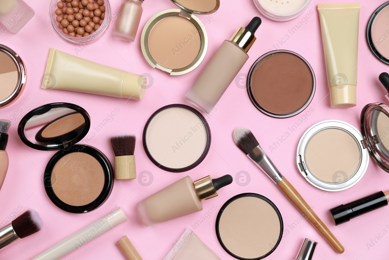 Photo of Face powders and other decorative cosmetic products on pink background, flat lay