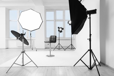 Interior of modern photo studio with bar stool and professional lighting equipment