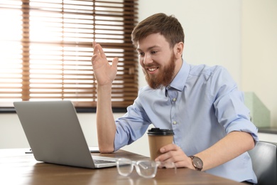 Photo of Man using video chat on laptop in home office