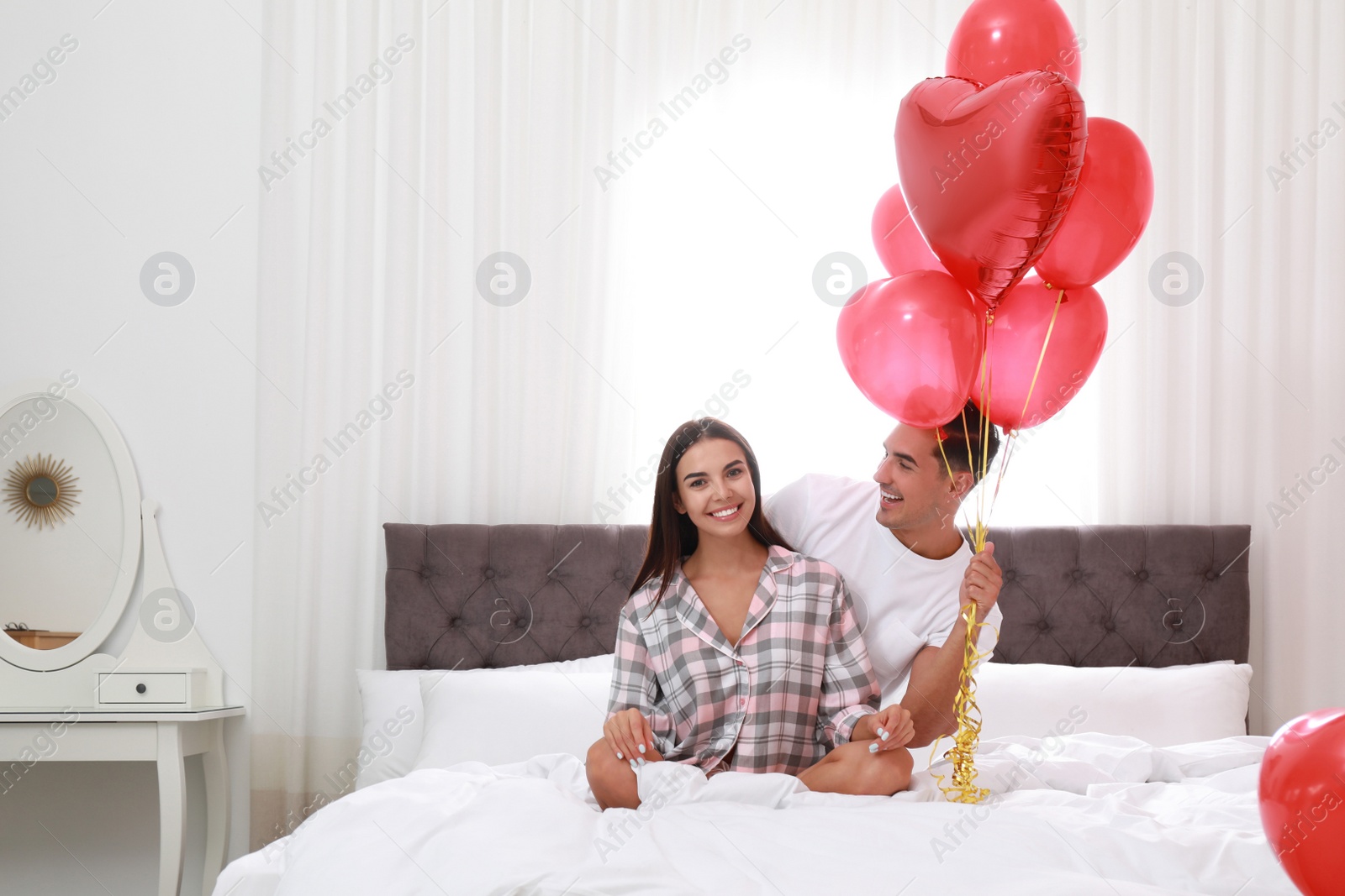 Photo of Beautiful couple with heart shaped balloons in bedroom