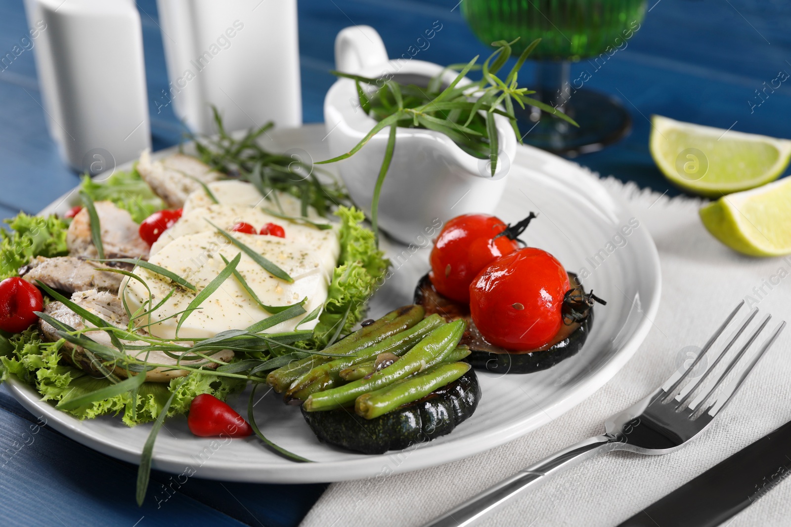 Photo of Tasty mozzarella, chicken and vegetables with tarragon served on blue table, closeup