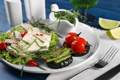 Tasty mozzarella, chicken and vegetables with tarragon served on blue table, closeup