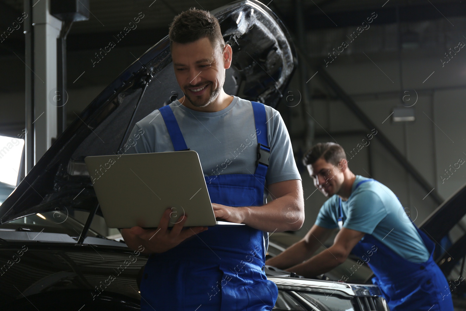 Photo of Mechanic with laptop doing car diagnostic at automobile repair shop