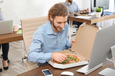Photo of Office employee having pizza for lunch at workplace. Food delivery