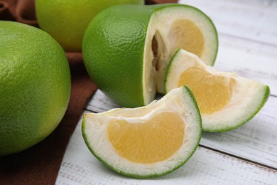 Whole and cut sweetie fruits on white wooden table, closeup