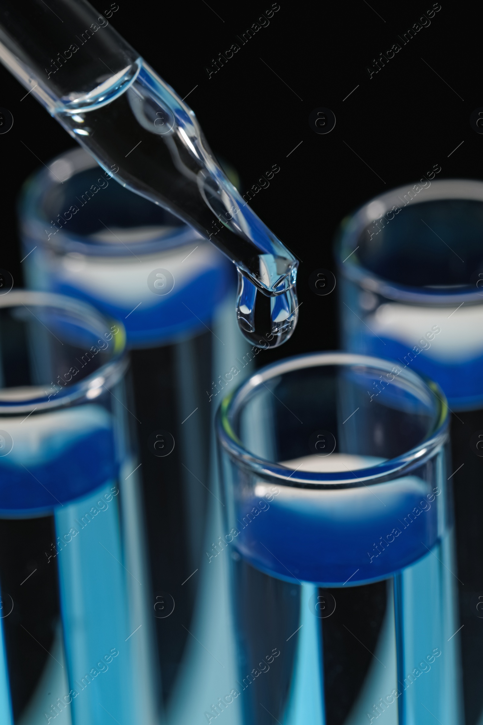 Photo of Dripping reagent into test tube on black background, closeup. Laboratory analysis