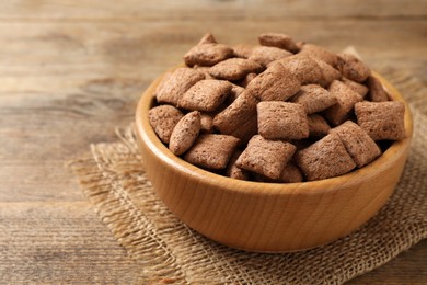 Sweet crispy corn pads in bowl on wooden table, closeup