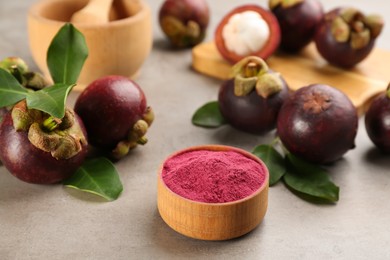 Purple mangosteen powder and fruits on light grey table