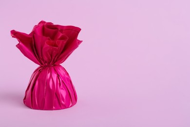 Candy in bright wrapper on pink background. Space for text