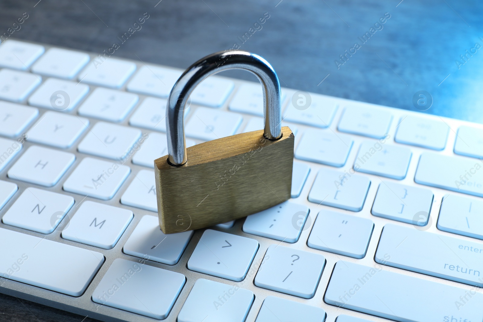 Photo of Cyber security. Metal padlock and keyboard on grey table, closeup