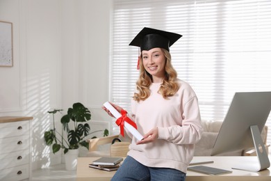 Happy student with graduation hat and diploma at workplace in office