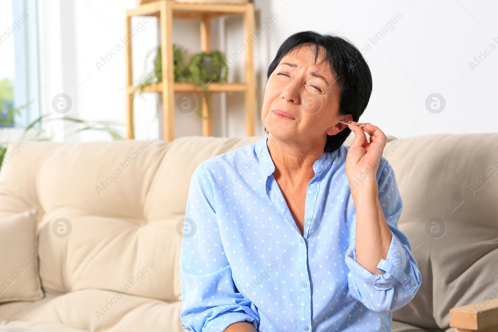 Photo of Senior woman cleaning ear with cotton swab at home. Space for text