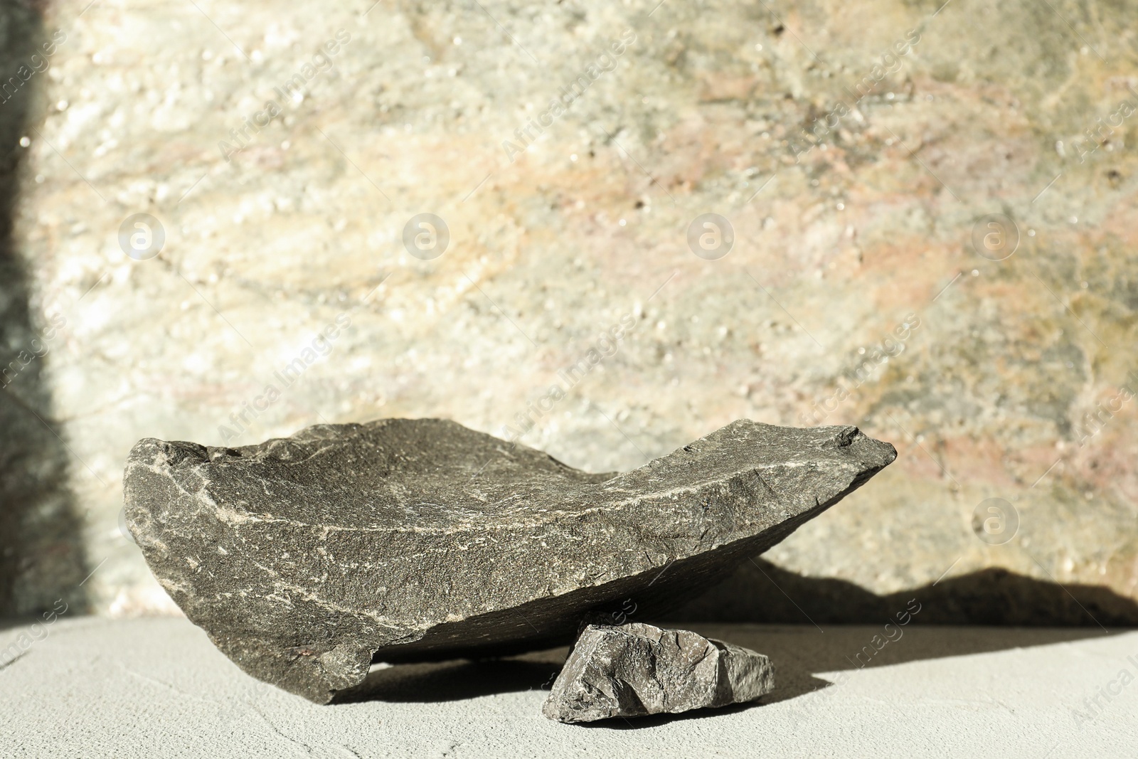 Photo of Presentation of product. Podium made of stones on light textured table. Space for text