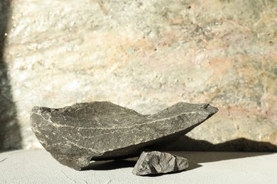 Photo of Presentation of product. Podium made of stones on light textured table. Space for text