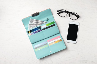 Photo of Smartphone, glasses and stylish wallet with cash and credit cards on light background, top view