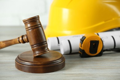 Photo of Construction and land law concepts. Judge gavel, protective helmet, drawings with tape measure on wooden table