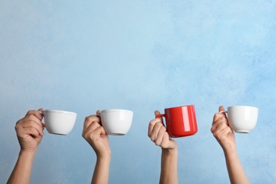 Woman holding different cup from others on color background