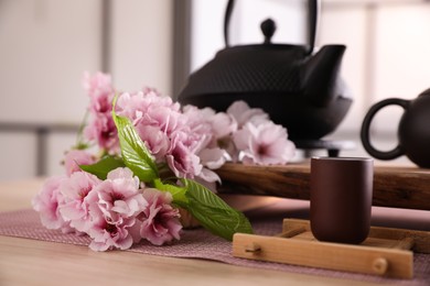 Photo of Cup and sakura flowers on wooden table. Traditional tea ceremony