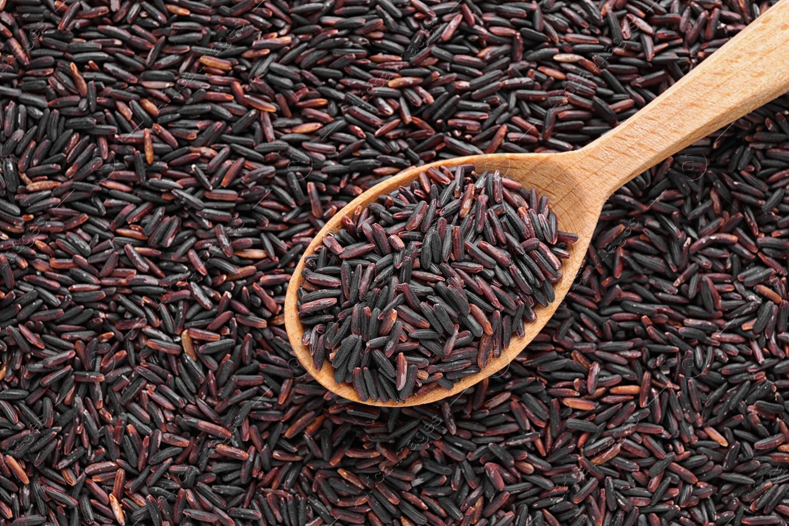 Photo of Pile of brown rice with spoon, top view