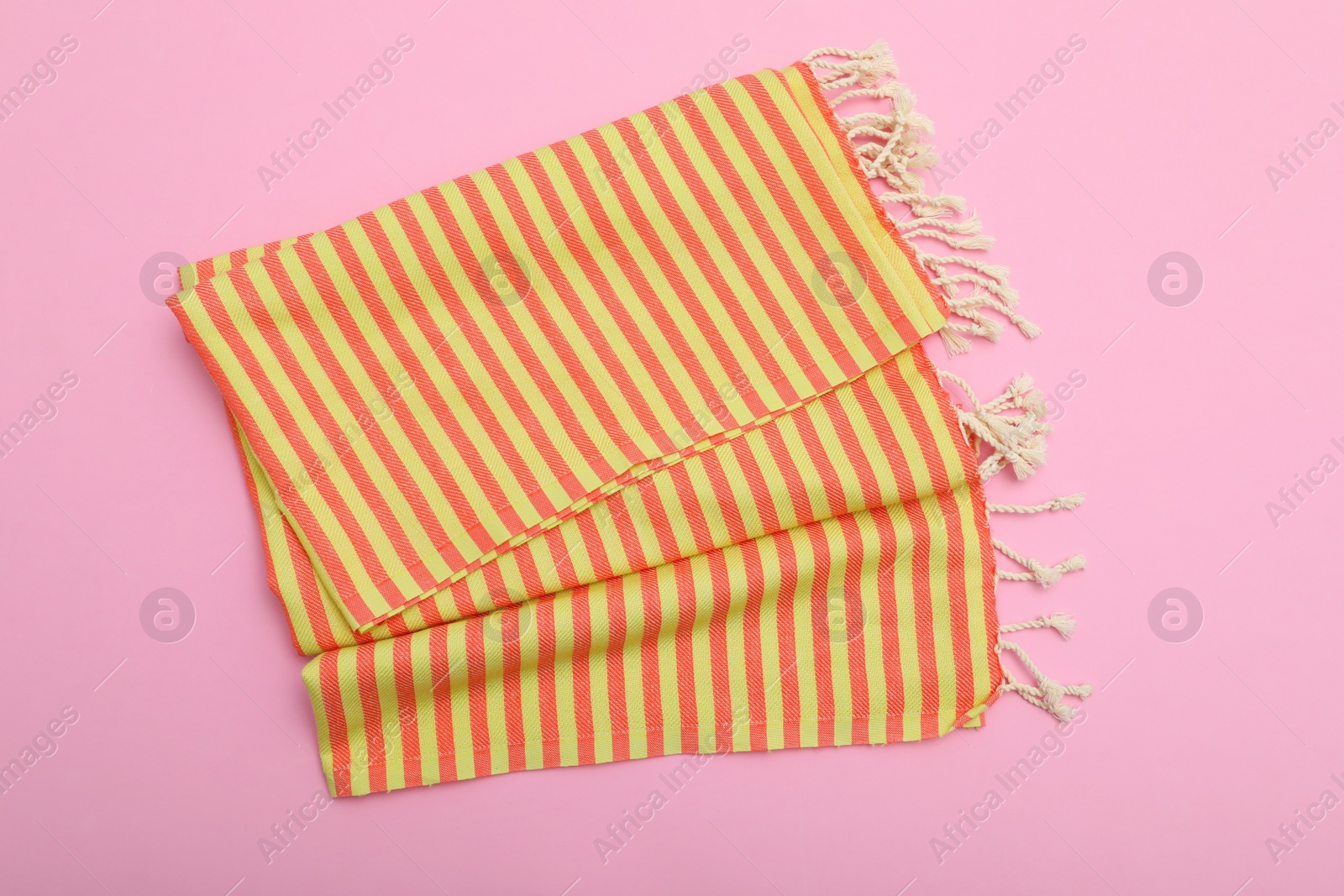 Photo of Folded striped beach towel on pink background, top view