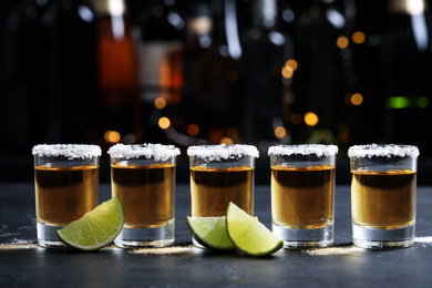 Photo of Mexican Tequila shots, lime slices and salt on bar counter