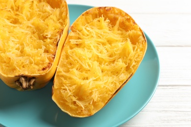 Plate with cooked spaghetti squash on white wooden background, closeup